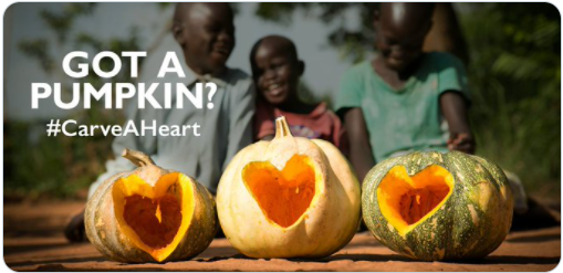 Three gords are shown with a heart carved into it. Three children are blurred in the background.